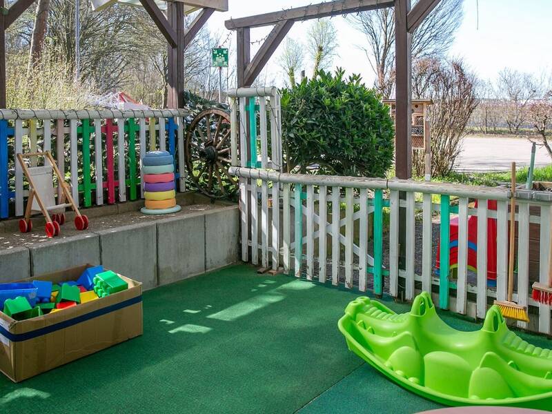 Ein fröhlich bunter Spielbereich im Außenbereich mit Spielgeräten für die Kleinsten