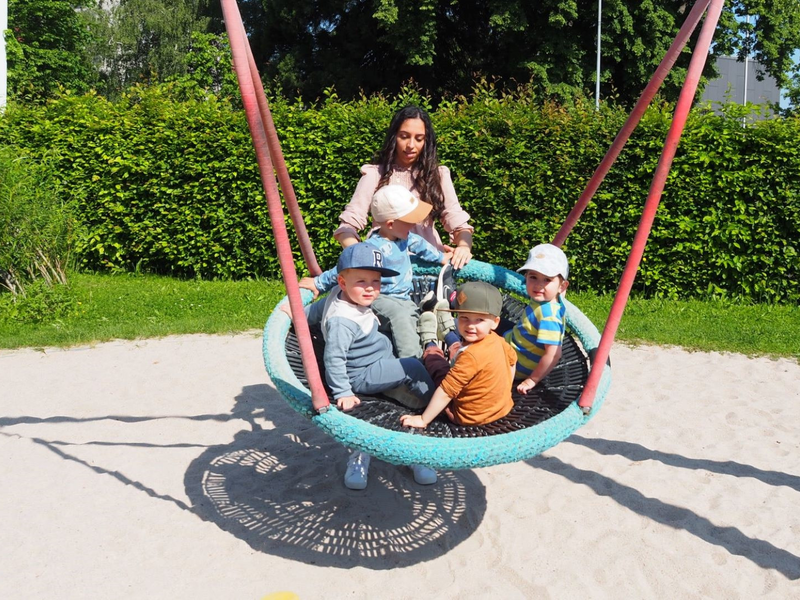 Eine Frau mit drei Kindern auf einer Nestschaukel