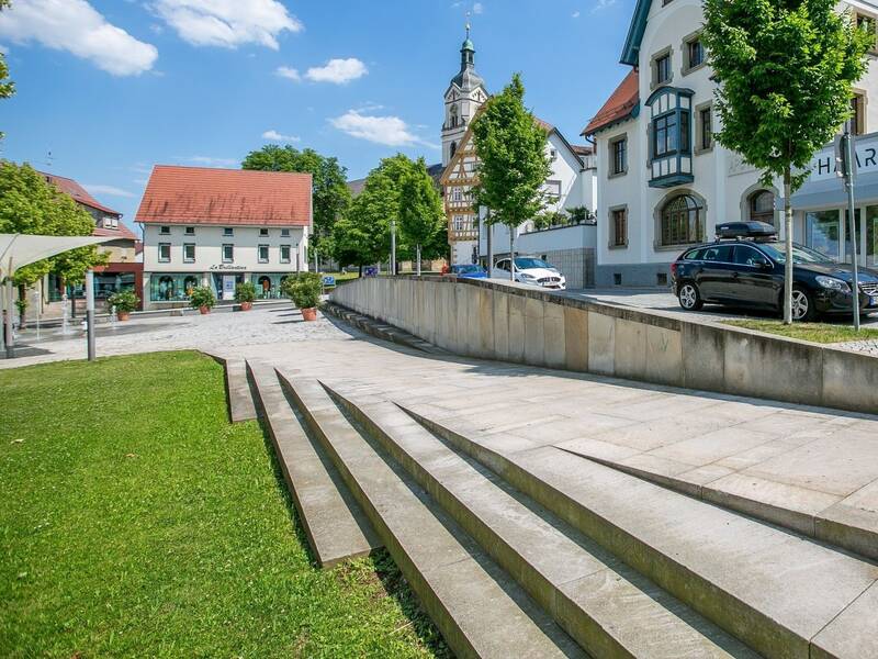 Stufen führen auf einen Platz, im Hintergrund befindet sich eine Kirche